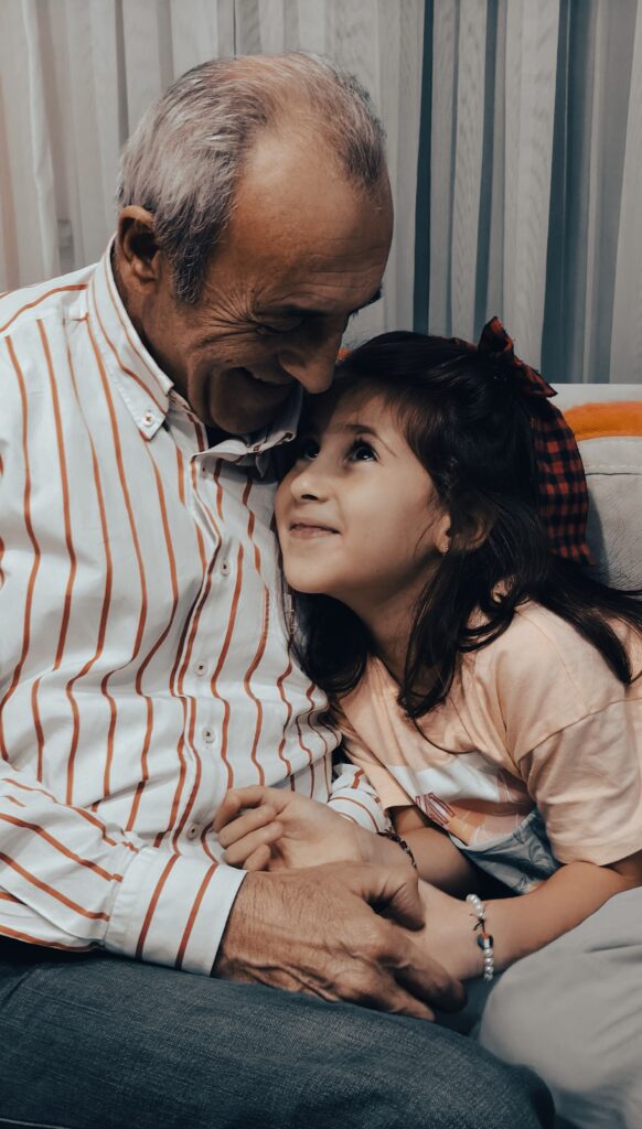 Grandfather and granddaughter sharing a laugh, representing the family voices and stories worth preserving.