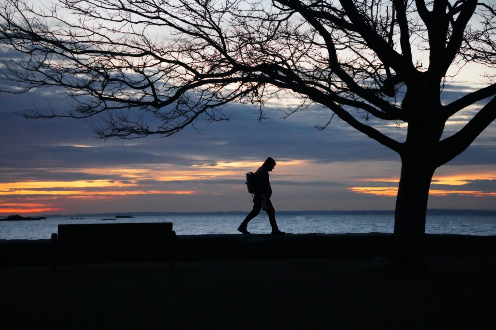 Person walking beside the ocean, symbolising self-trust and moving forward after making a choice.