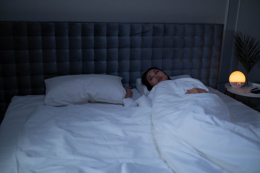Person lying awake in bed at night while struggling with racing thoughts.