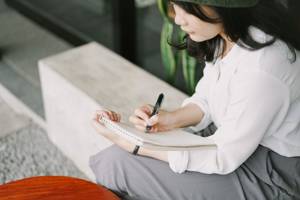 Person recording daily reflections to become more present and remember meaningful experiences.