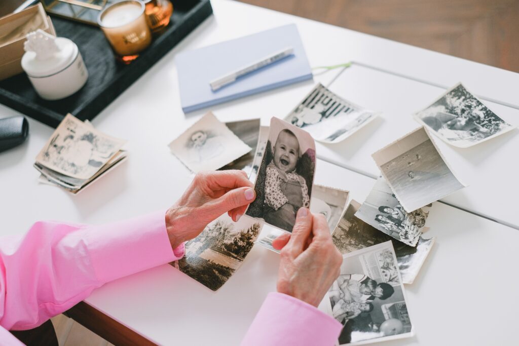 Hands exploring old photographs and memories as part of reconnecting with personal identity.