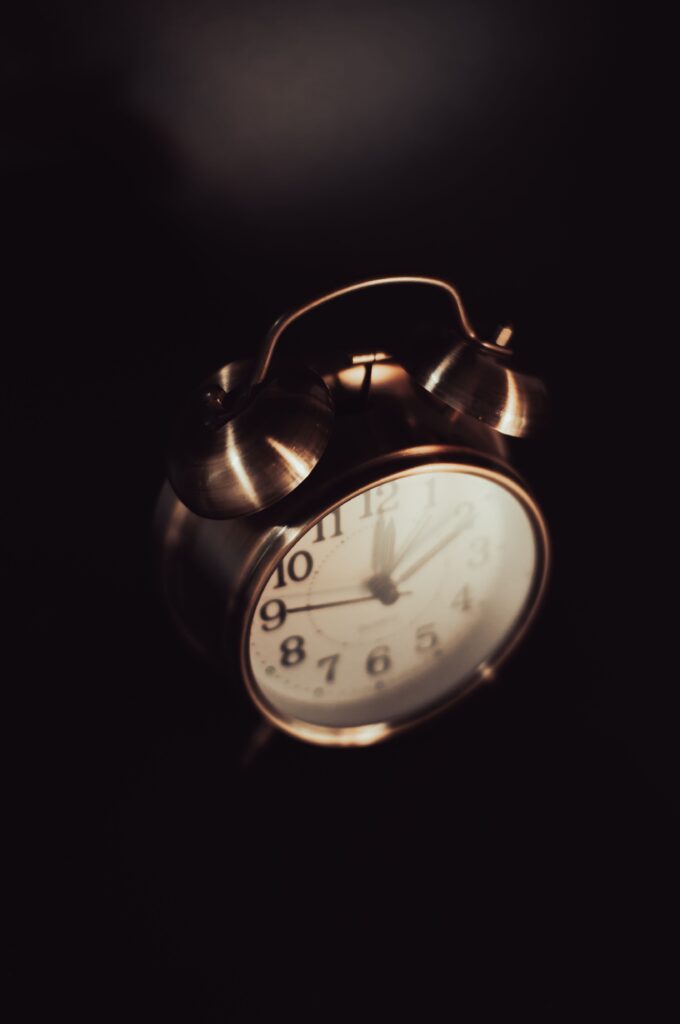 Bedside clock in a dark room illustrating sleeplessness and night-time overthinking.